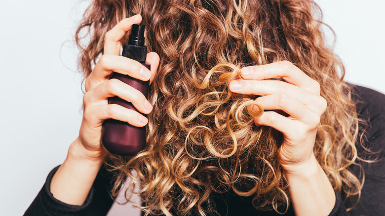 Woman spraying product on curly hair