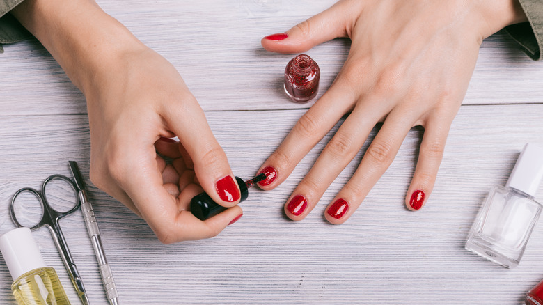 Closeup of woman painting fingernails on tabletop 