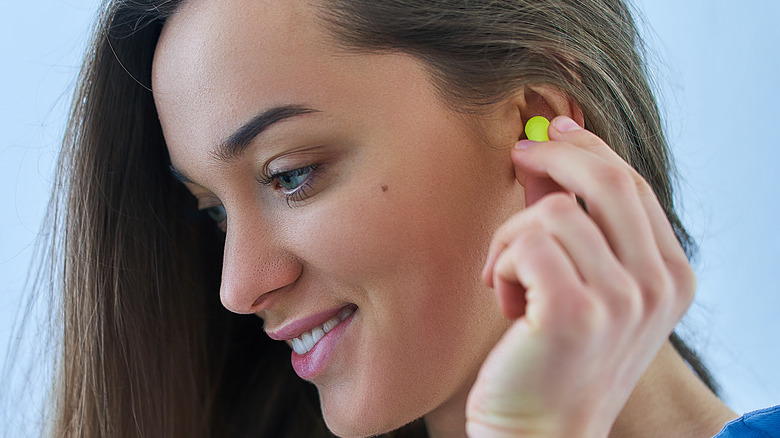 Woman putting earplug in ear