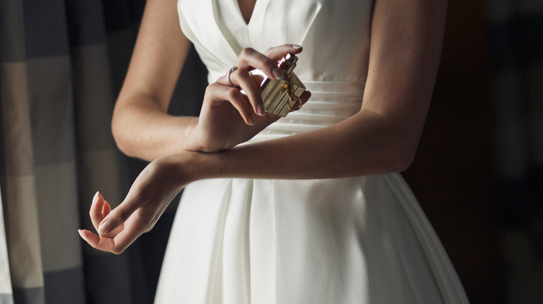 woman rubbing wrists with perfume 