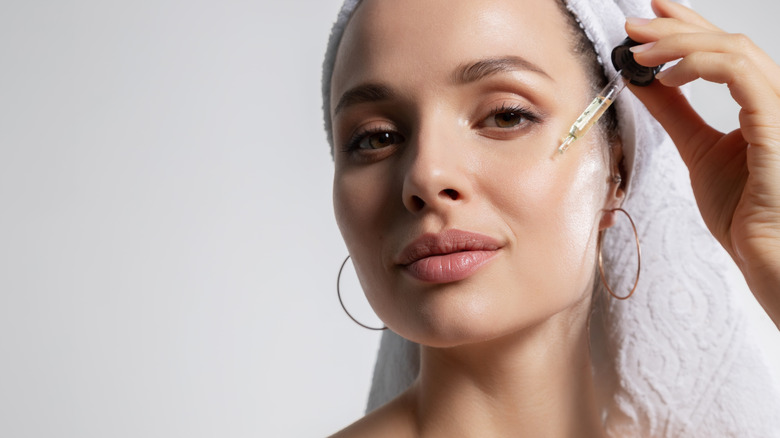 close up of woman using oil on face