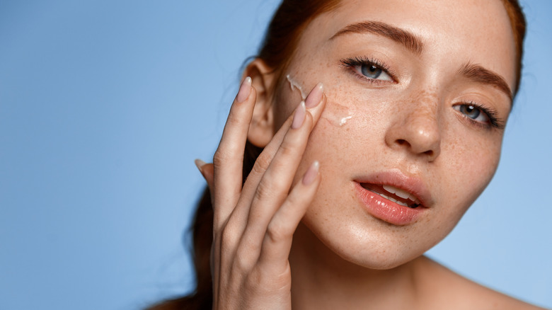 close up image of woman applying oil on face