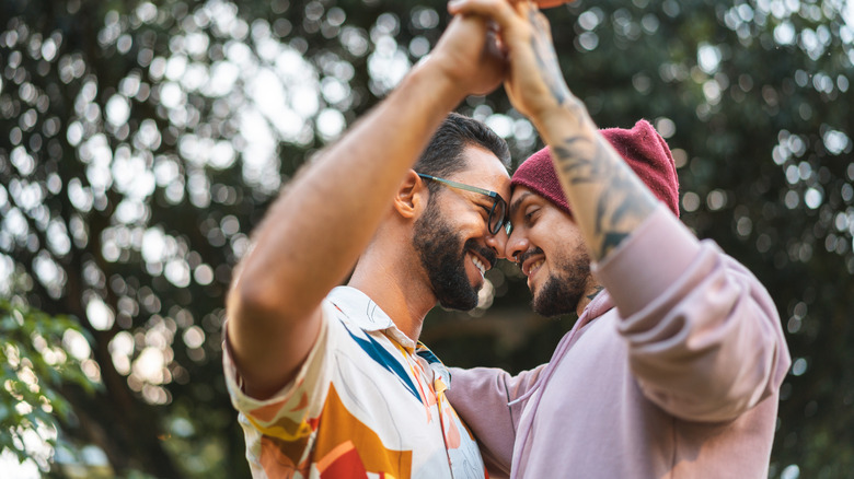 Two men holding hands and smiling outdoors