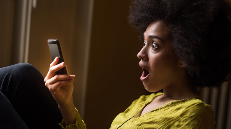 woman shocked holding phone