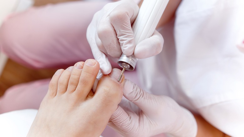 pedicurist filing toenails