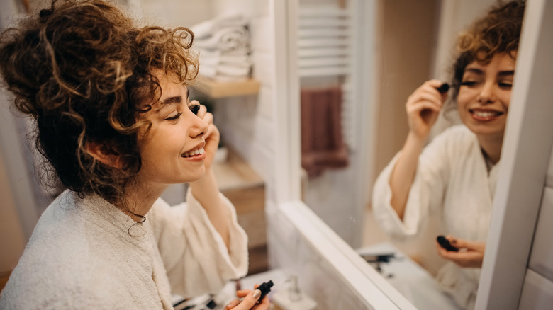 Woman doing her makeup in mirror