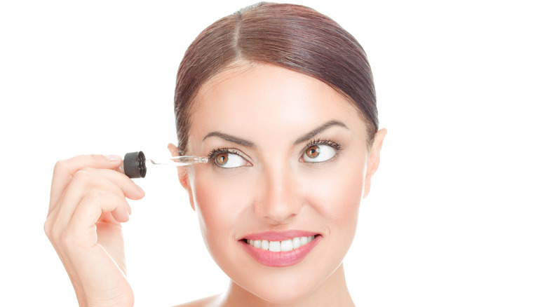 Woman applying conditioner serum to eyelashes