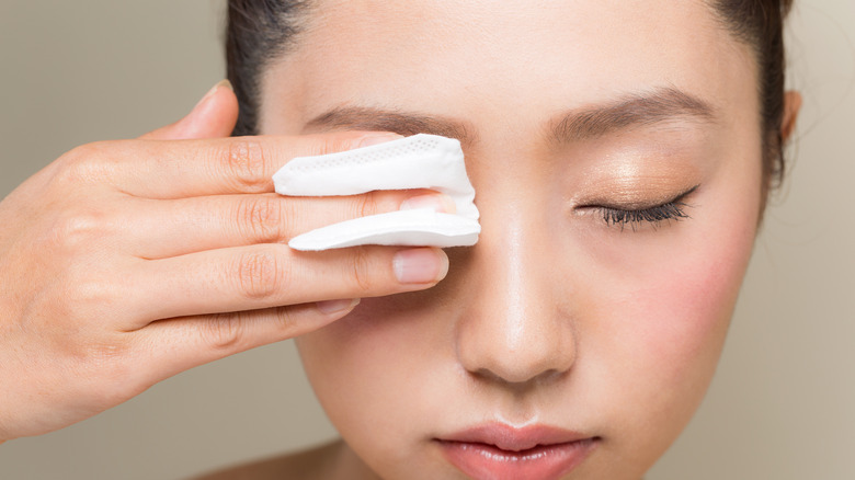 Woman holding cotton pad on her eye