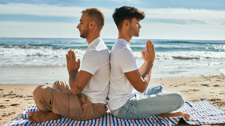 couple doing yoga and meditation on beach