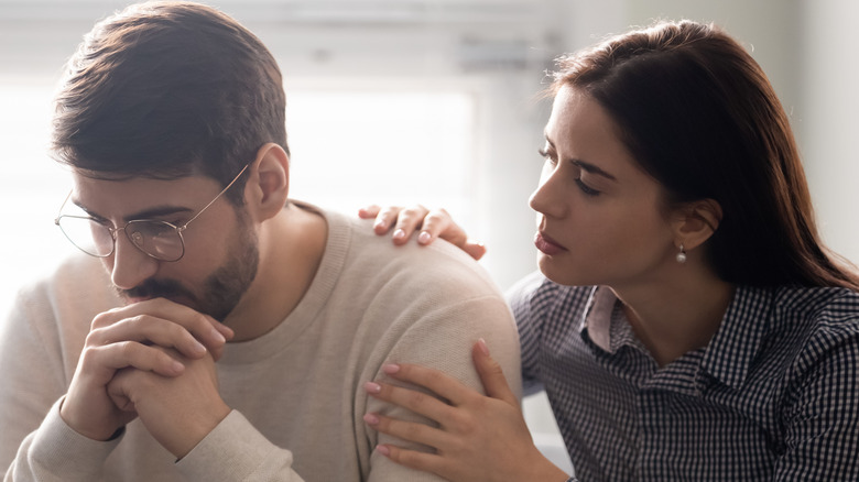 woman consoling man with glasses