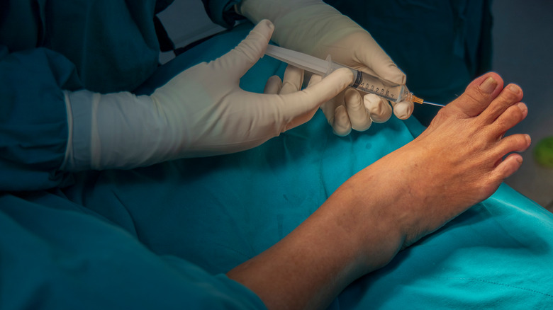 Doctor injecting needle in patient's foot