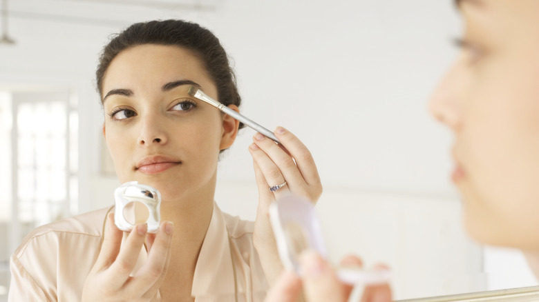 Woman applies eyeshadow base