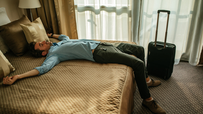 Exhausted man on hotel bed