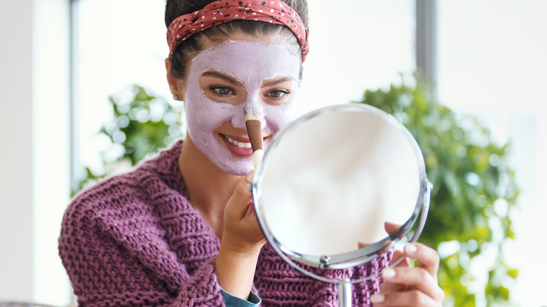 woman applying clay mask