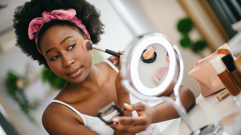 woman applying makeup to face