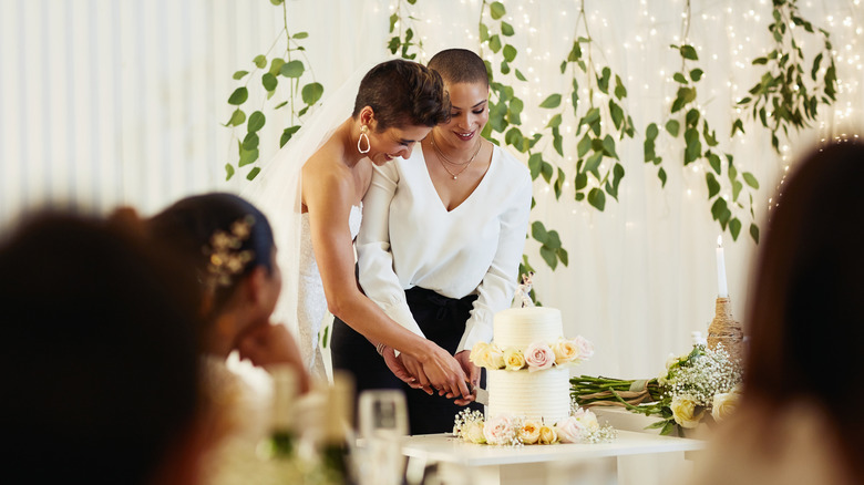 Two brides cutting their wedding cake 