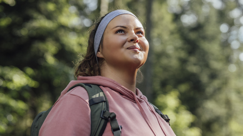 Woman smiling wearing a backpack and sweatshirt