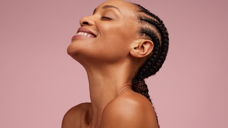 Smiling woman with clear skin against mauve background