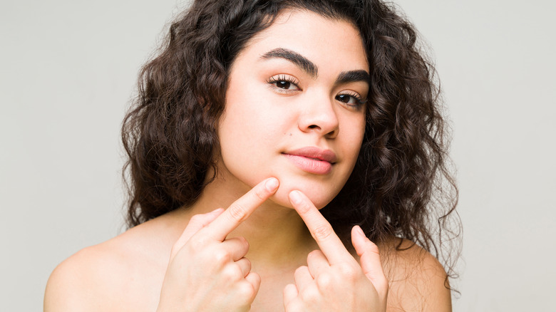 Woman pointing at blemish on chin