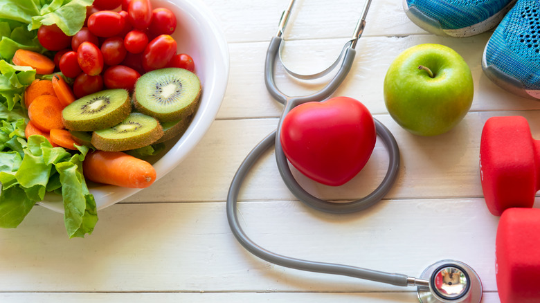 vegetables in a bowl, apple, exercise gear, stethoscope, and heart-shaped ball on table