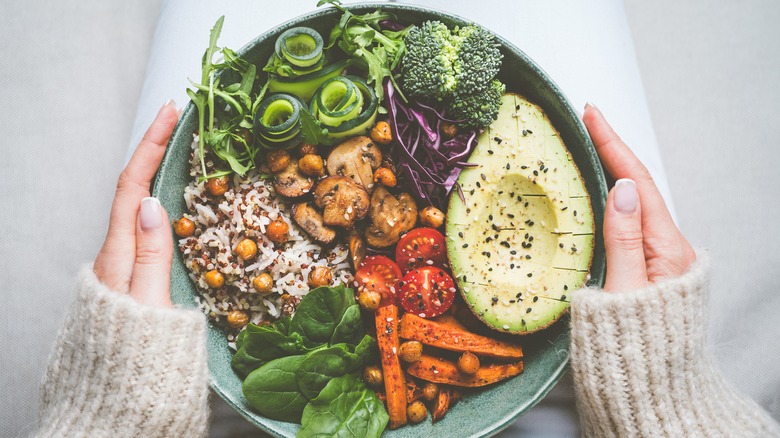 hand holds bowl of plant-based meal