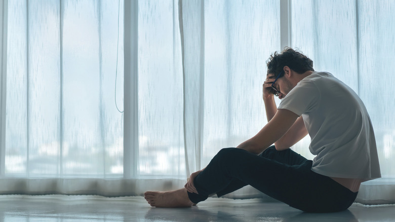 Upset man thinking by a window