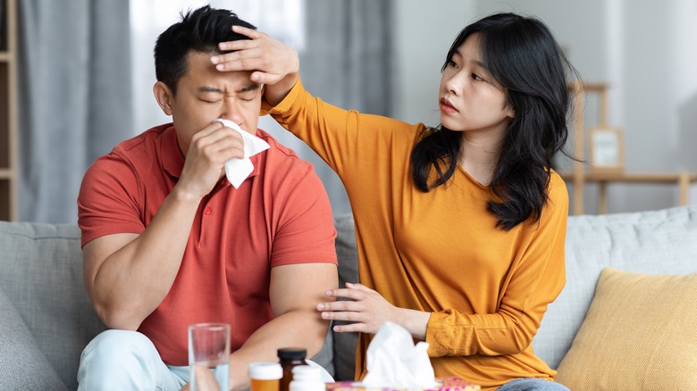 Woman feeling sick man's forehead