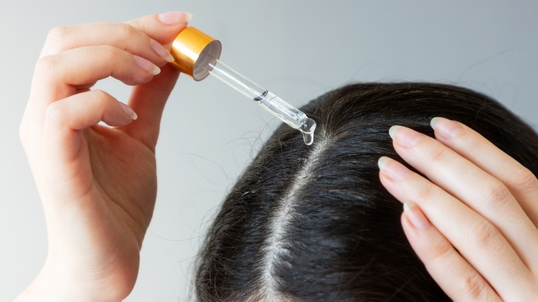 person applying oil to hair