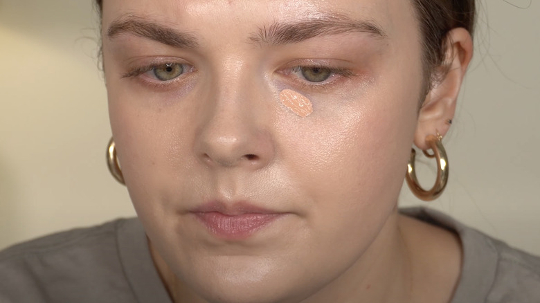 woman applying peach concealer