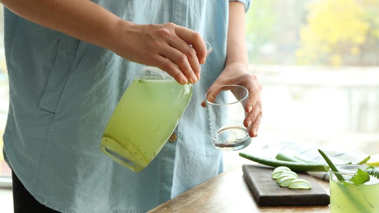 man pouring aloe vera juice into a glass 