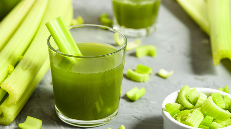 small glass of celery juice surrounded by pieces of celery