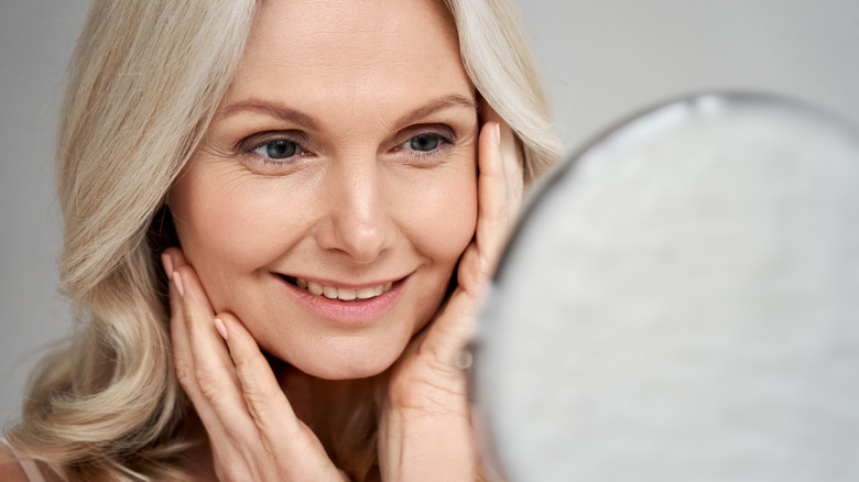 Smiling woman looks in mirror