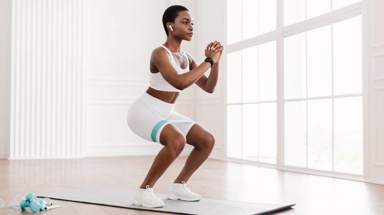 Woman doing sqats on a mat