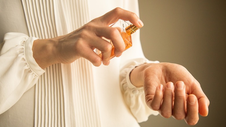 Person spraying perfume on their wrists