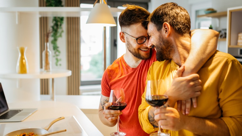 Gay couple hugging drinking wine