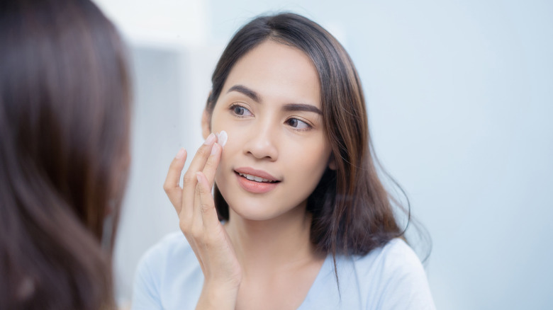 woman rubbing cream on skin