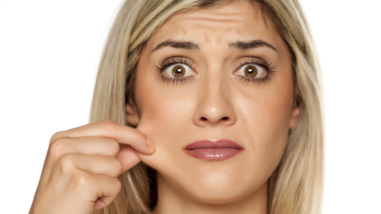 Blonde woman holding out her cheek