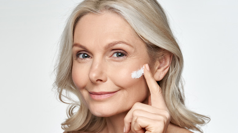 A woman applying face cream