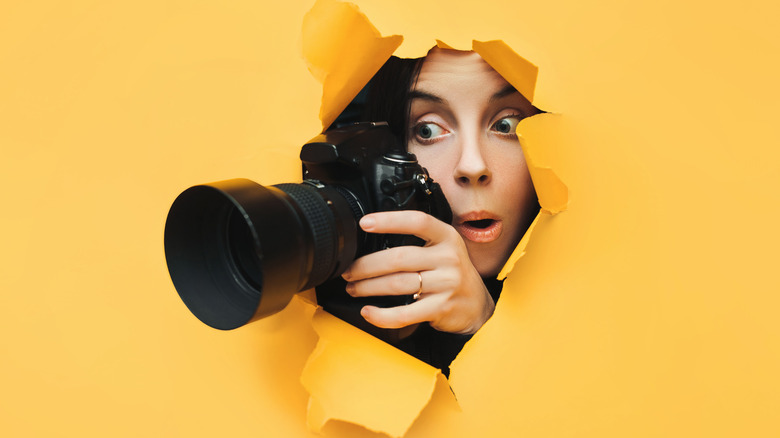woman with camera burst through yellow background