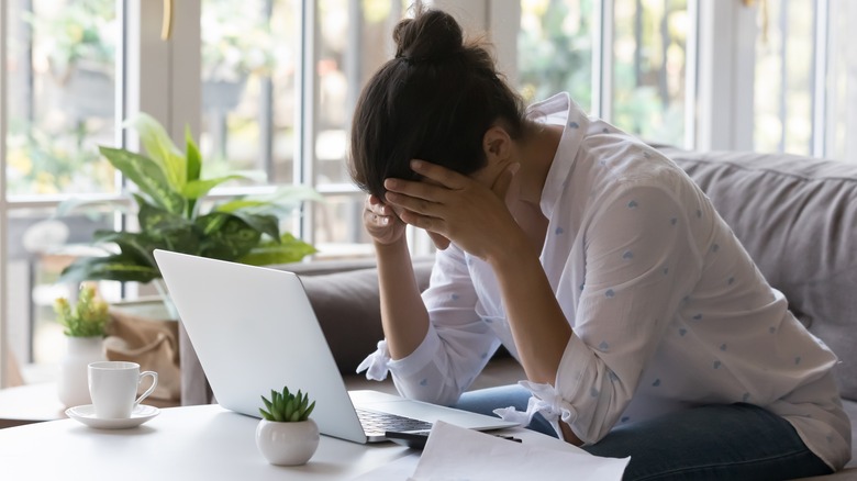 Woman struggling as she works on laptop