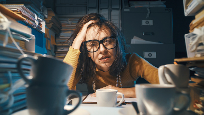 Woman staring blankly from cluttered work desk