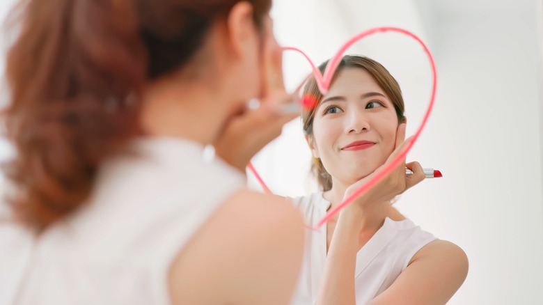 a girl looking lovingly at herself in the mirror with a heart drawn on it