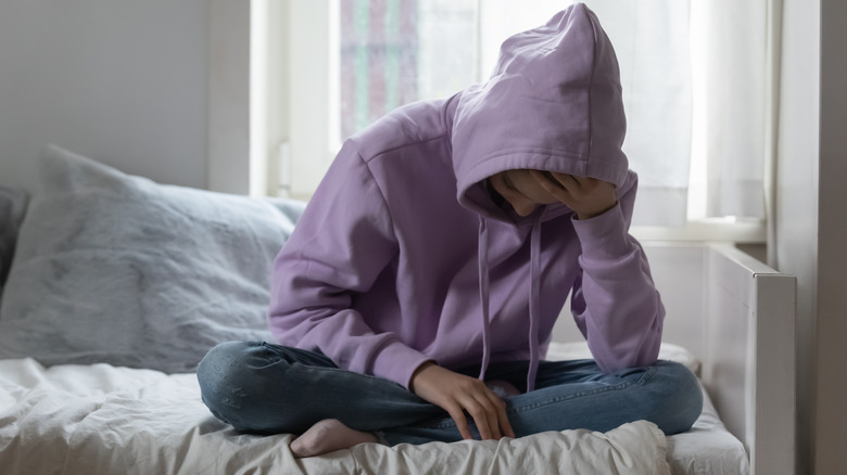 teen girl sitting on a her bed looking stressed or troubled