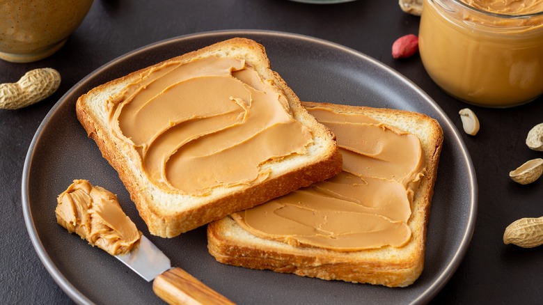 Peanut butter on toast alongside unshelled peanuts