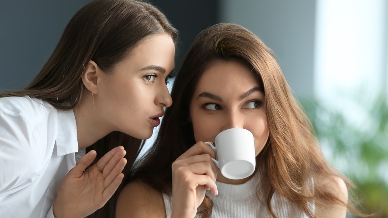 Woman gossiping to another woman