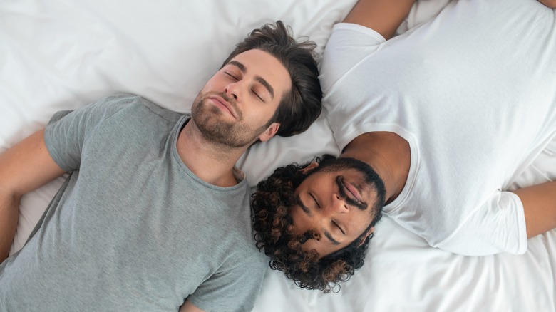 Gay couple asleep on white bed