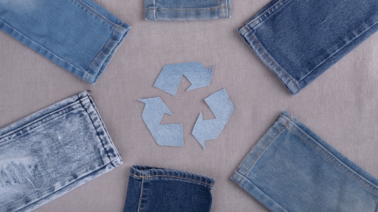 Pairs of jeans in a circle with a denim recycling symbol