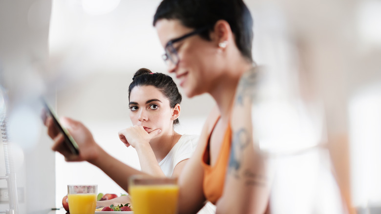 woman watching partner using phone