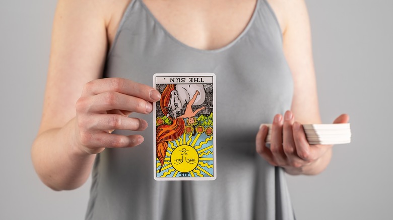 Woman holding reversed Sun card