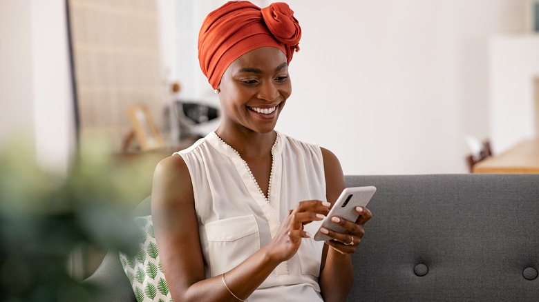 black woman with hair wrapped smiling at phone